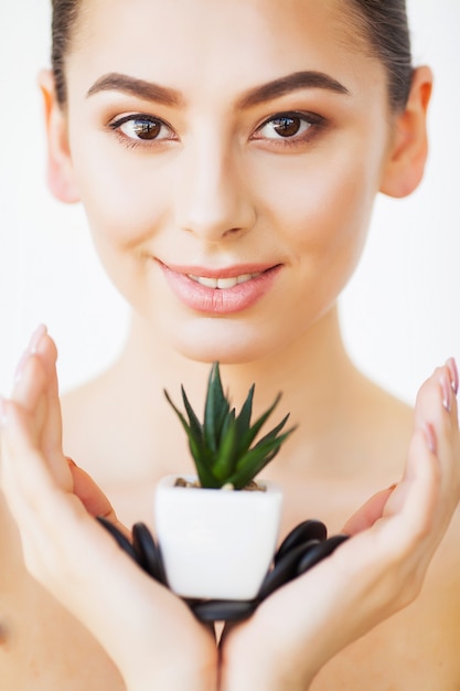 Soins de la peau. Visage de femme de beauté avec une peau saine et une plante verte.