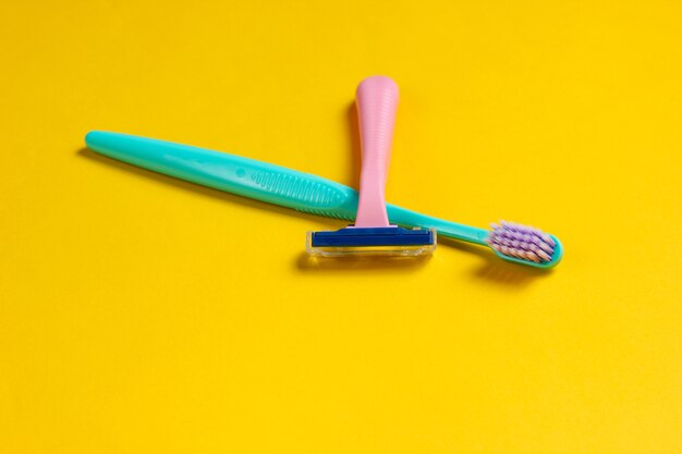 Soins personnels minimalistes, concept de beauté. Rasoir en plastique, brosse à dents sur jaune.