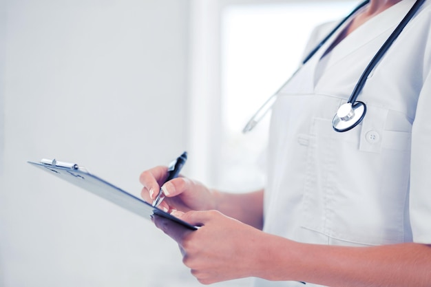 Soins de santé et concept médical - femme médecin avec prescription d'écriture stéthoscope