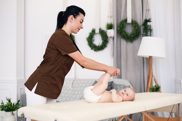 Soins de santé et concept médical. Une masseuse féminine professionnelle fait un massage et de la gymnastique à un petit bébé dans une chambre confortable et moderne.