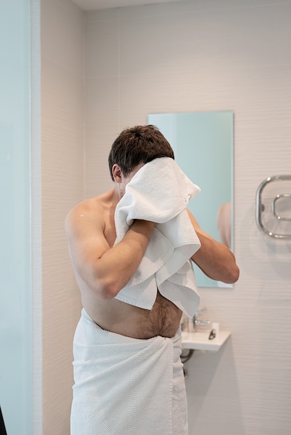 Soins de santé, hygiène dentaire. Jeune homme adulte se brosser les dents dans la salle de bain, regardant le miroir