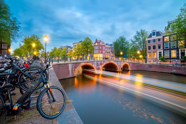 Photo soirée à amsterdam vues panoramiques sur les célèbres vieilles maisons vélos pont et canal dans le vieux centre longue exposition amsterdam hollande pays-bas europe