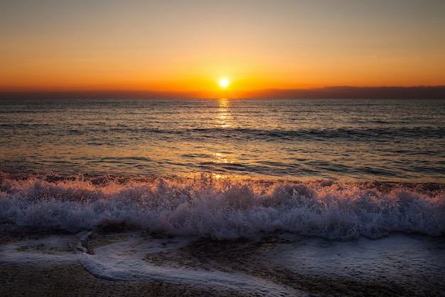 Soirée au soleil couchant sur la plage avec le surf en mer