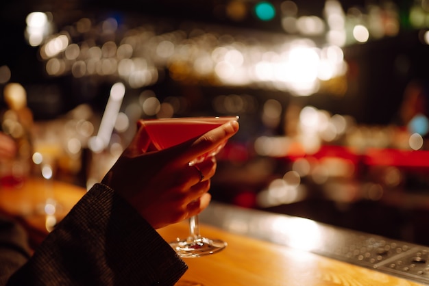 Soirée cocktails. ?ocktail dans les mains d'une femme. Jeune femme buvant des cocktails au bar.