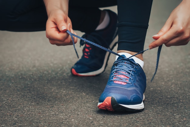 Soirée courir. Jeune femme en cours d&#39;exécution sur une route rurale pendant le coucher du soleil en baskets bleus