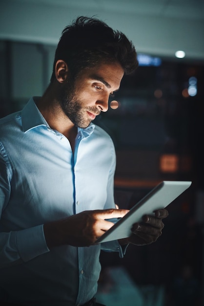 Soirée d'homme d'affaires et lecture avec une tablette pour la recherche, le réseautage ou la vérification de la connectivité au bureau Employé ou support technique travaillant tard sur la technologie pour la navigation ou la connexion Internet