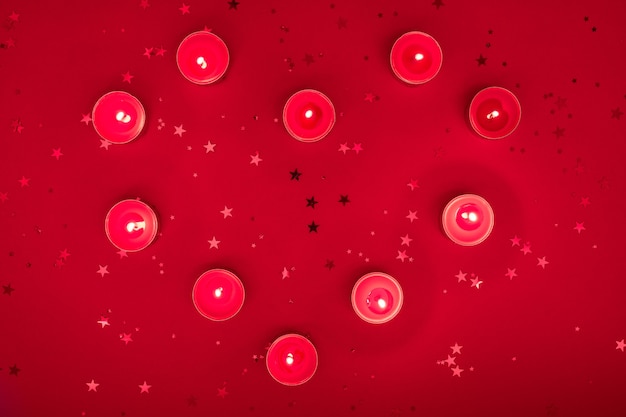 Soirée de Noël ou composition de la Saint-Valentin à base de bougies allumées, paillettes sur une surface rouge