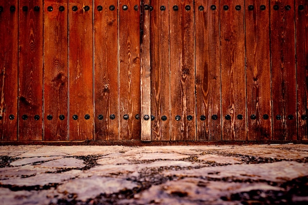 Sol pavé et porte en bois vieillie dans la ville. Sol en pierre et fond de mur.