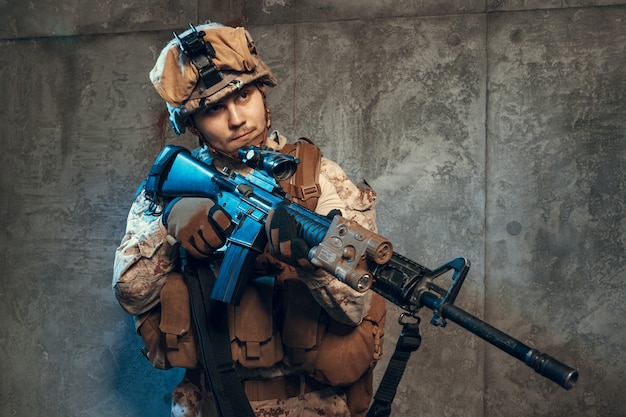 Soldat de l'armée entièrement équipé, portant un uniforme et un casque de camouflage, armé d'un pistolet et d'un fusil de service d'assaut
