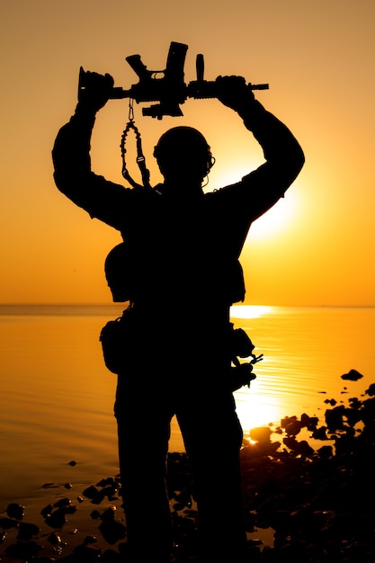 Soldat De L'armée Avec Fusil Au-dessus De Sa Tête Silhouette Coucher De Soleil. Concept De Victoire