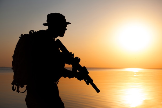 Soldat de l'armée avec silhouette coucher de soleil orange fusil