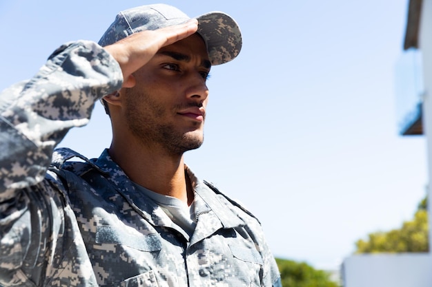 Soldat biracial portant un uniforme militaire, saluant à l'extérieur, avec espace de copie. Mode de vie, service militaire et temps libre, inchangés.