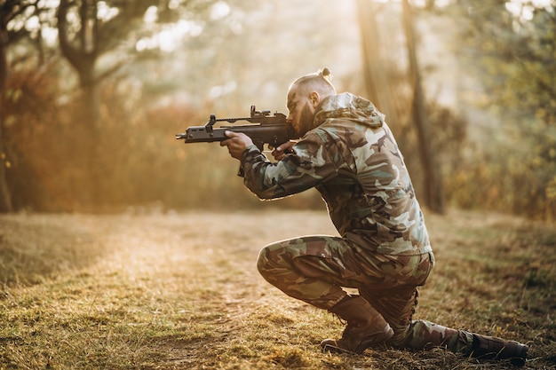 Soldat de camouflage jouant airsoft à l'extérieur dans la forêt