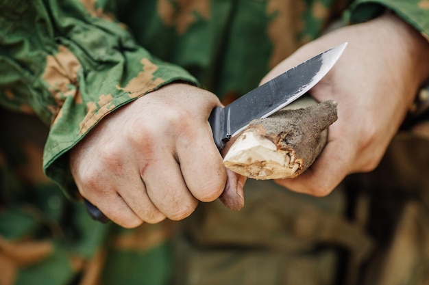 Le soldat avec un couteau a coupé un bâton en bois