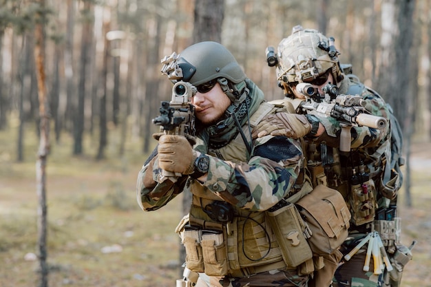 Un soldat dans un uniforme militaire spécial avec un casque sur la tête et avec un fusil de sniper dans le for