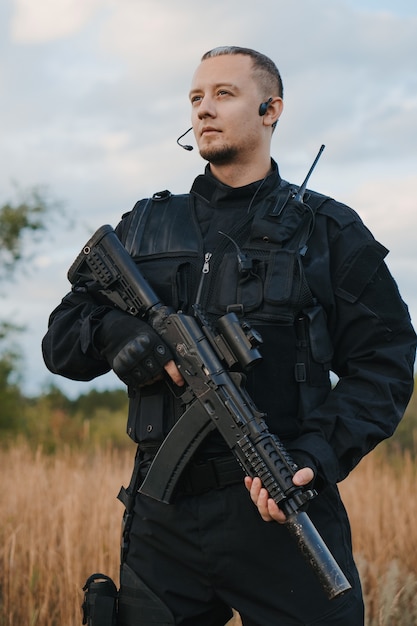 Soldat de la force spéciale en uniforme noir avec un fusil d'assaut