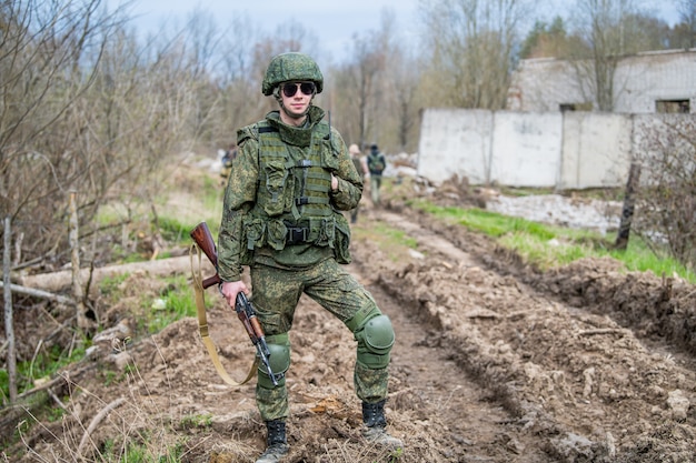 Soldat avec le fusil et les jumelles en uniforme de camouflage et tonneau