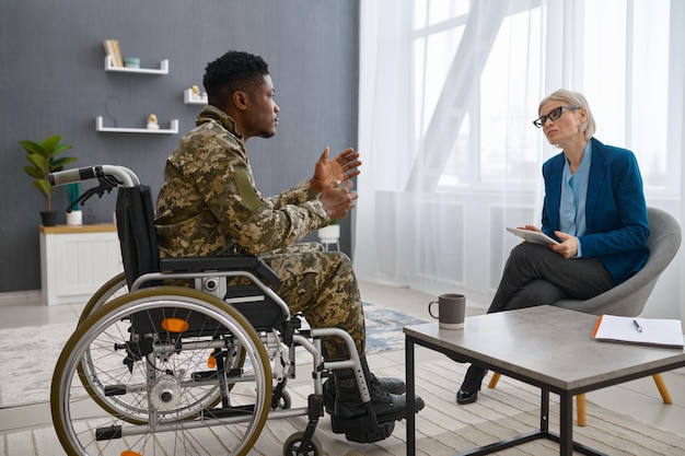 Soldat handicapé en fauteuil roulant visitant un psychologue. Consultation psychologique professionnelle