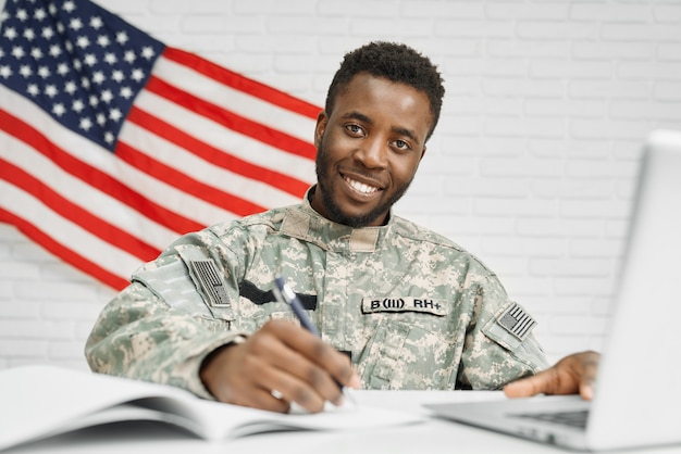 Soldat heureux assis sur le lieu de travail et écrit dans les documents.