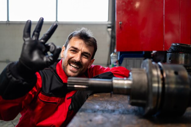 Un soldat heureux dans l'atelier près des pièces de rechange.