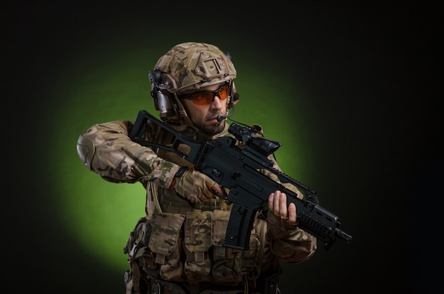 Un soldat masculin en vêtements militaires avec une arme sur un fond sombre