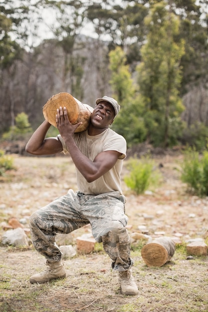 Photo soldat militaire portant une bûche d'arbre pendant la course d'obstacles dans le camp d'entraînement