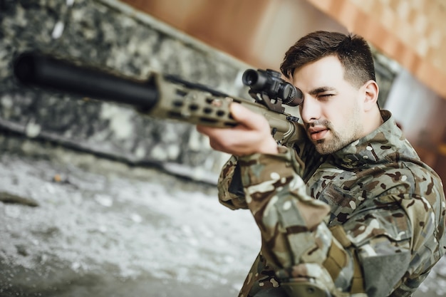 Un soldat militaire vise et tient un grand fusil dans le bâtiment.