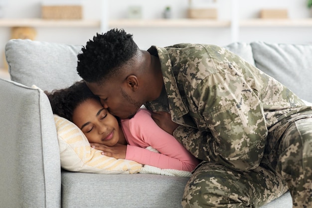 Soldat noir de retour pour le service militaire embrassant sa fille endormie