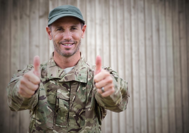 Soldat pouce levé contre un panneau de bois flou