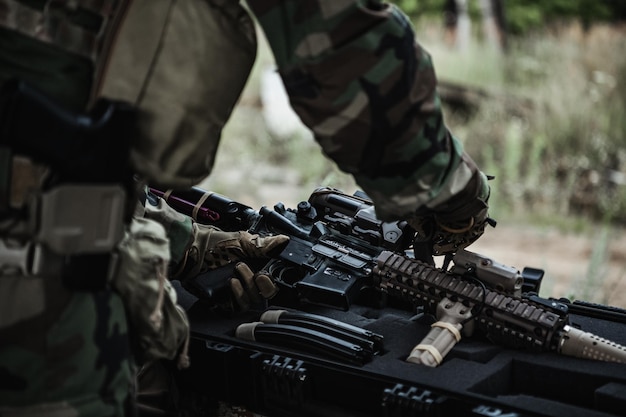 Le soldat sort un fusil de la boîte à munitions et insère le clip de munition dans le fusil d'assaut