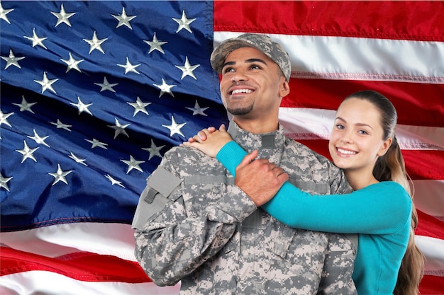 Soldat souriant avec sa femme debout sur fond de drapeau américain