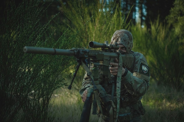 Un soldat en tenue de camouflage avec une mitrailleuse dans l'herbe