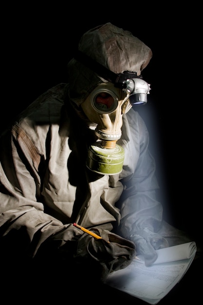 Soldat en tenue de protection et masque à gaz avec bloc-notes et crayon lors du briefing.