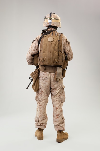 Soldat en uniforme de marine américain avec fusil sur gris clair, prise de vue en studio