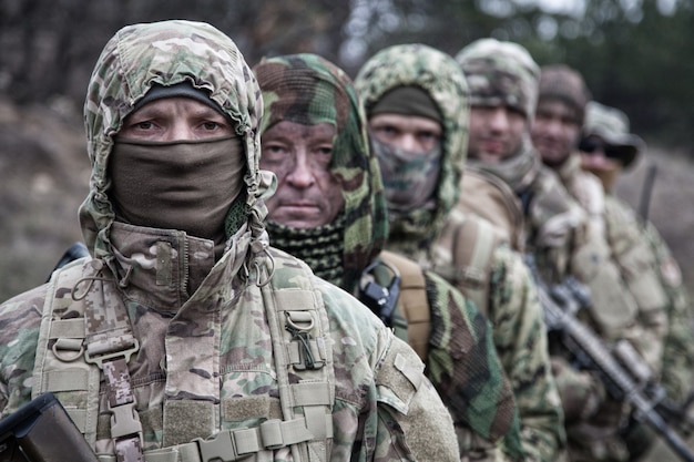 Soldats du groupe tactique des forces d'élite de l'armée, escouade de commandos qualifiés, membres portant un uniforme de camouflage, cachant les visages derrière des masques, faisant la queue derrière le commandant