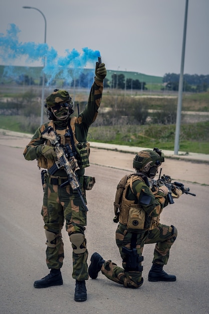 Soldats des forces spéciales menant une opération à l'aide de fusils d'assaut et d'une bombe fumigène bleue