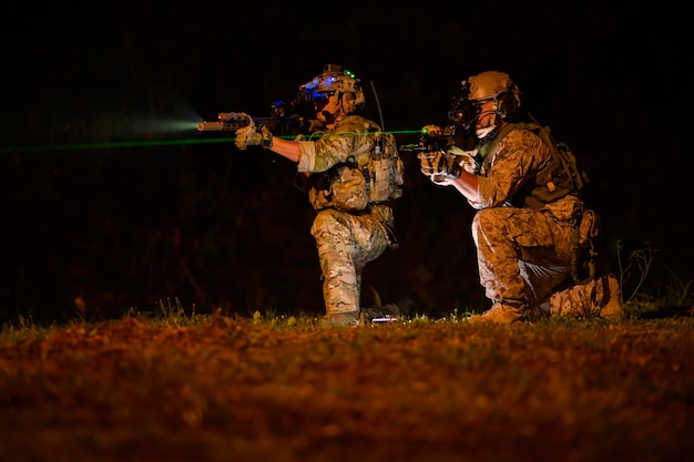 Des soldats prêts à tirer pendant une opération militaire de nuit.