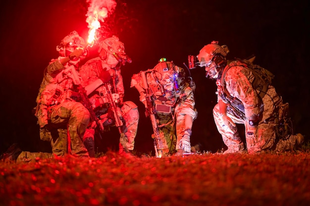 Photo des soldats en uniforme de camouflage visant avec leurs fusils pendant l'opération militaire de nuit.