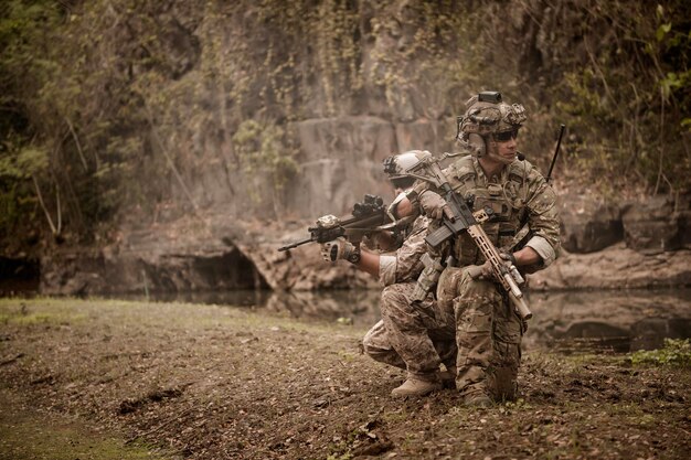 Des soldats en uniforme de camouflage visant avec leurs fusils.