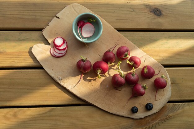 Le soleil de l'après-midi brille sur la plaque en bois, radis rouge complet et tranché
