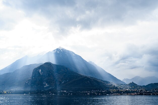 Le soleil brille à travers les nuages au-dessus des sommets des montagnes lac de côme italie