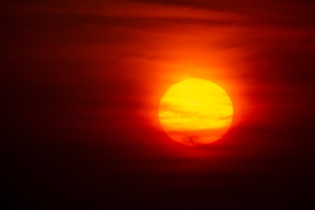 Soleil cramoisi brillant sur fond de coucher de soleil ou d'aube