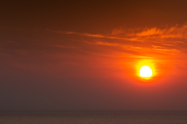 Soleil cramoisi brillant sur fond de coucher de soleil ou d'aube