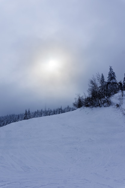 Soleil dans la brume sur la pente de la montagne enneigée