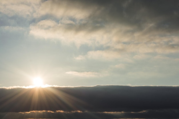 Photo soleil derrière de beaux nuages blancs à midi