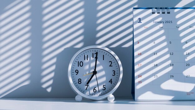 Soleil du matin et ombre sur la surface de l'horloge de table ronde blanche avec calendrier de bureau sur tableau blanc