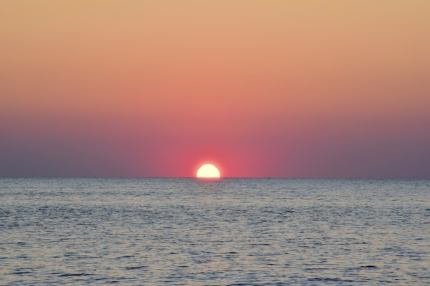 Le soleil du matin se levait à moitié de la mer calme.