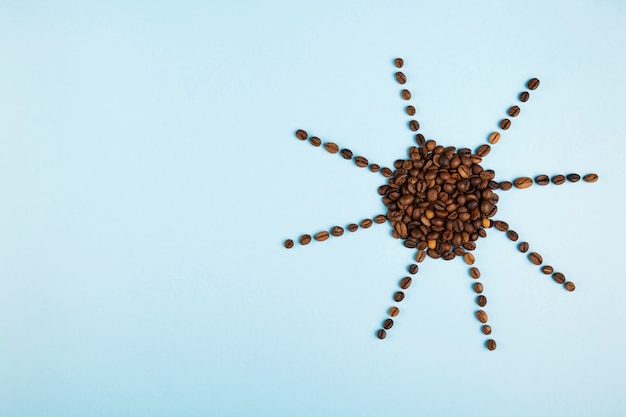 Soleil Fait De Grains De Café Sur Fond Bleu. Le Concept Commence Le Matin Avec Un Café. Vue De Dessus, Surface