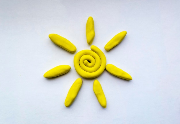 Soleil jaune de pâte à modeler sur feuille de papier blanc