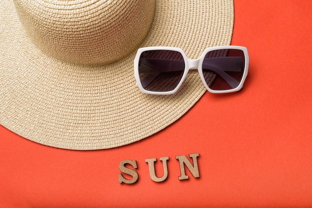 Soleil de mot de lettres en bois. Lunettes de soleil et chapeau. Fond de corail vivant. Concept de voyage